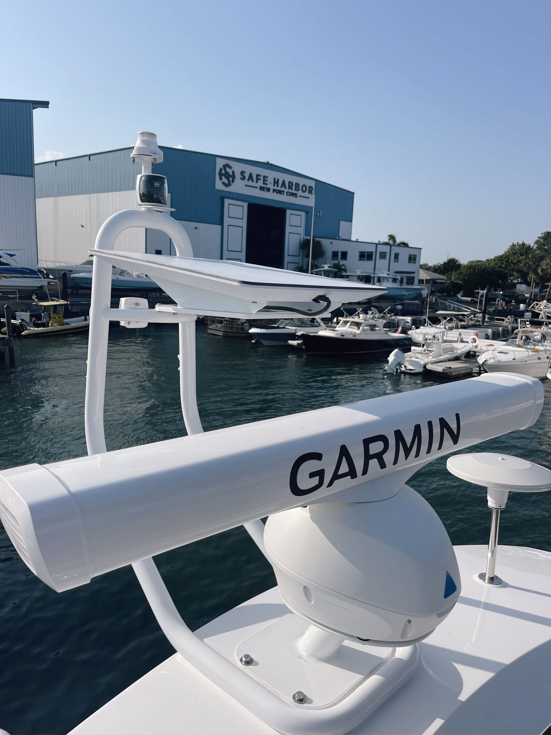 GARMIN radar mounted on a boat, with a marina and waterfront buildings in the background