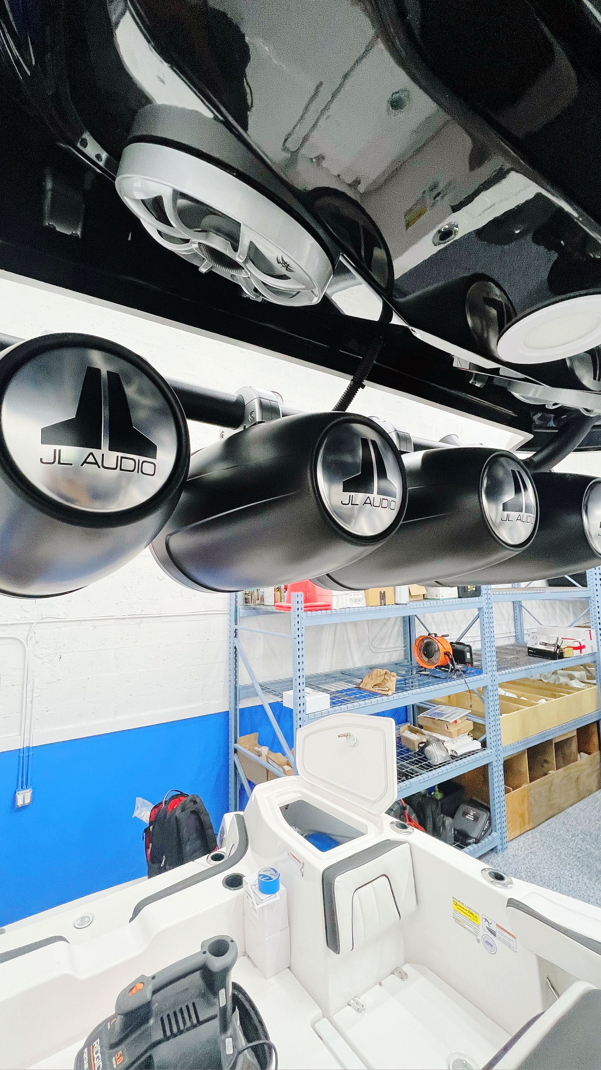 A boat is sitting in a garage with a lot of lights hanging from the ceiling.