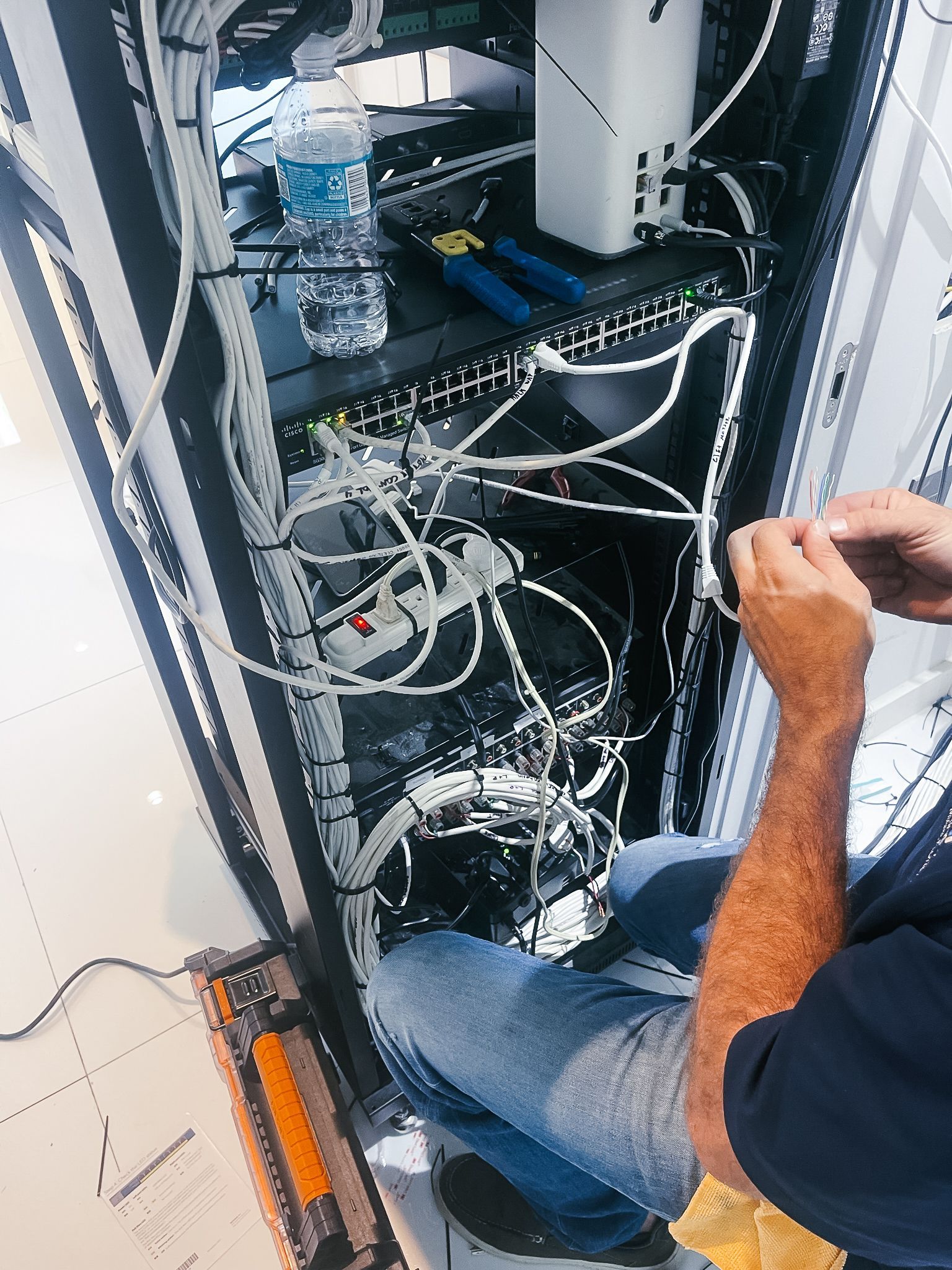 A man is working on a computer in a server room.
