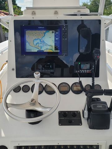 Boat dashboard with navigation screen, steering wheel, gauges, and radio.