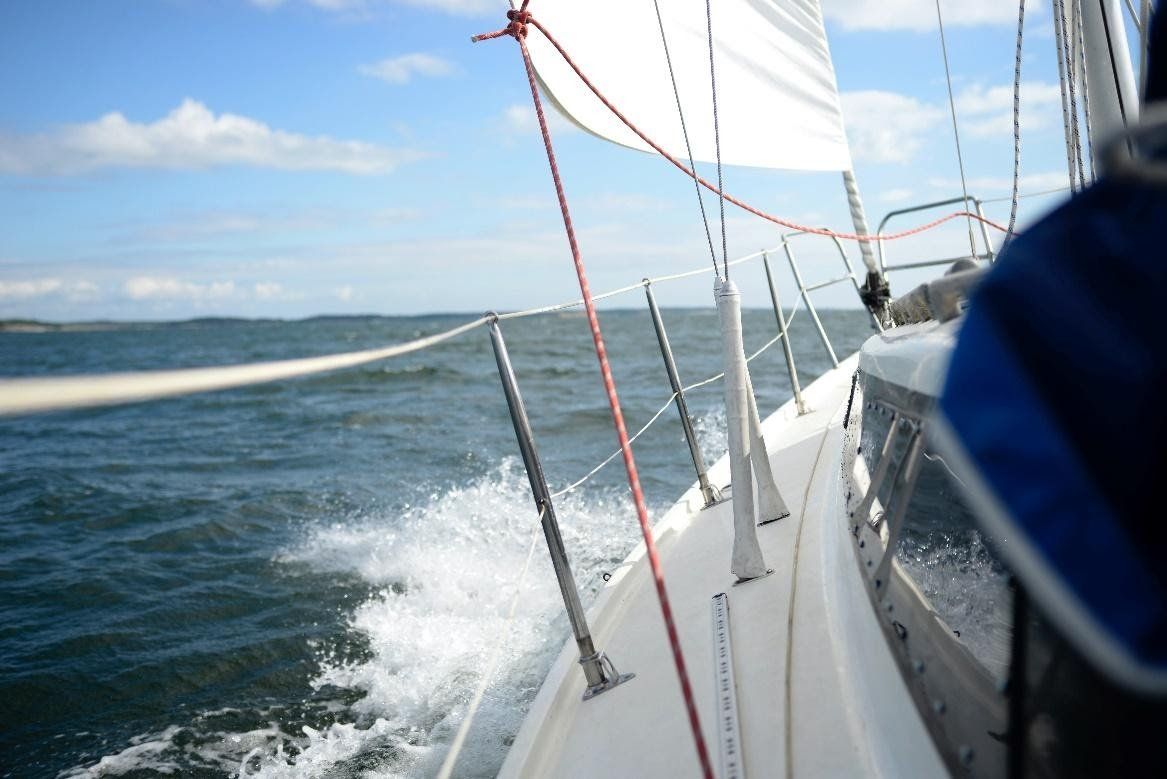 A sailboat is going through the ocean on a sunny day