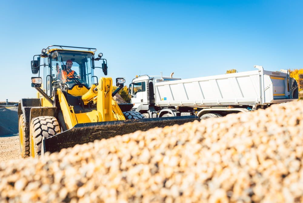 A Bulldozer Is Loading a Dump Truck with Gravel on A Construction Site — Barry's Recycling in Redland Bay, QLD