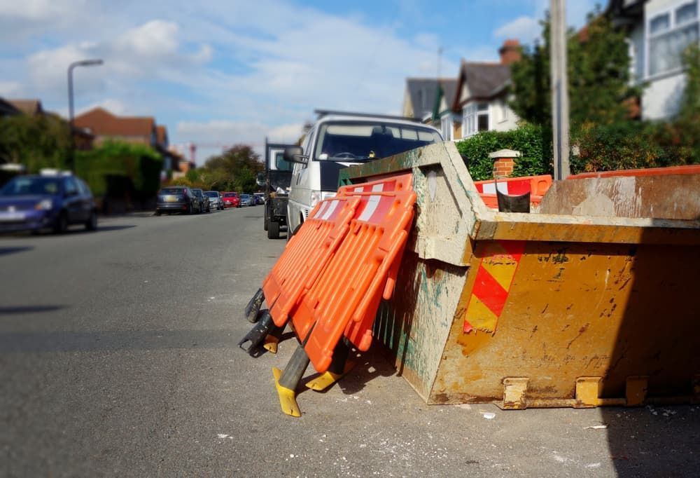 A Dumpster Is Sitting on The Side of The Road Next to A Row of Orange Barriers — Greenline Recycling in Brisbane, QLD