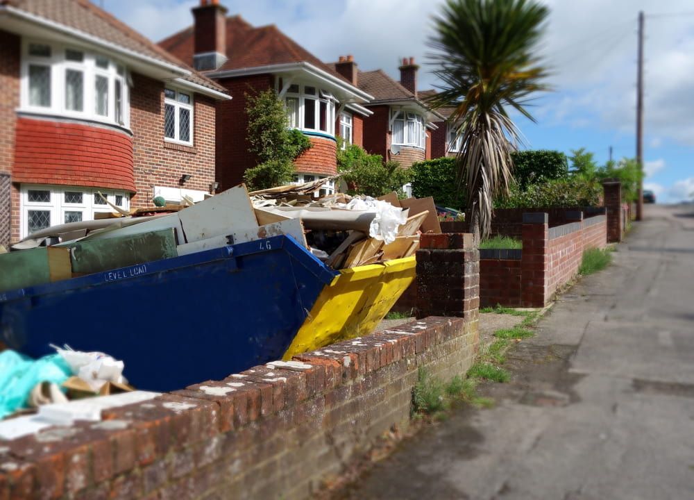 A Blue and Yellow Dumpster Is Sitting Next to A Brick Wall — Greenline Recycling in Redland Bay, QLD