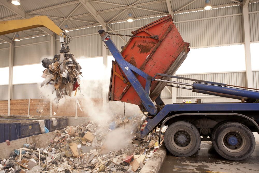 A Dump Truck Is Being Loaded with Garbage in A Warehouse — Barry's Recycling in Redland Bay, QLD