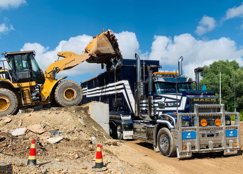 A Construction Worker Is Holding a Piece of Wood in Front of A Building — Greenline Recycling in Brisbane, QLD