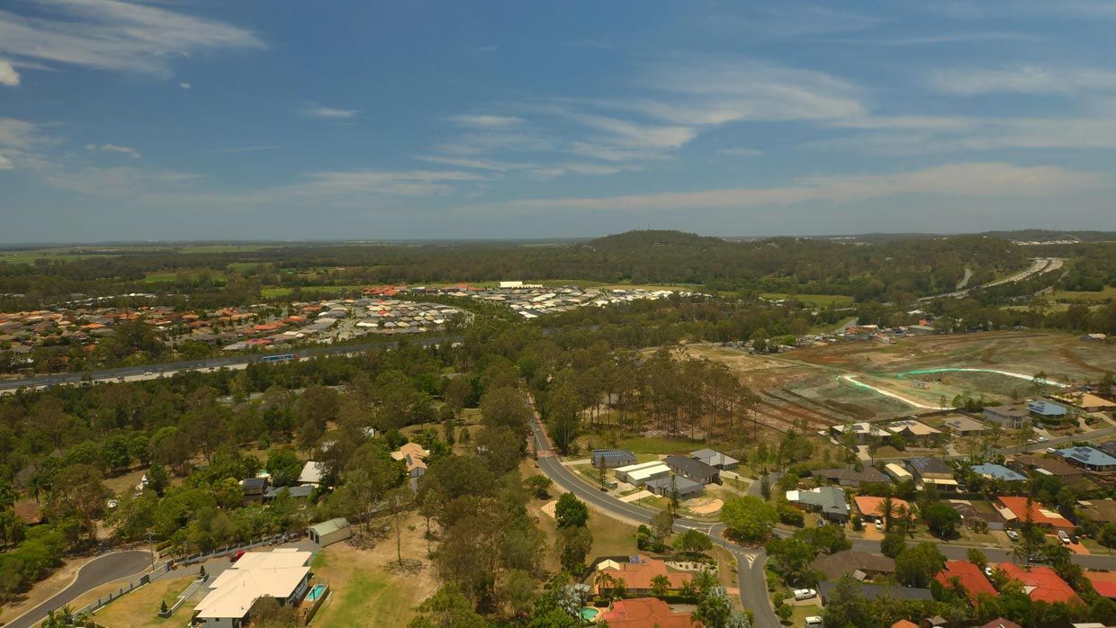 An Aerial View of a Residential Area Surrounded by Trees and Houses on a Sunny Day — Barry's Recycling in Ormeau, QLD