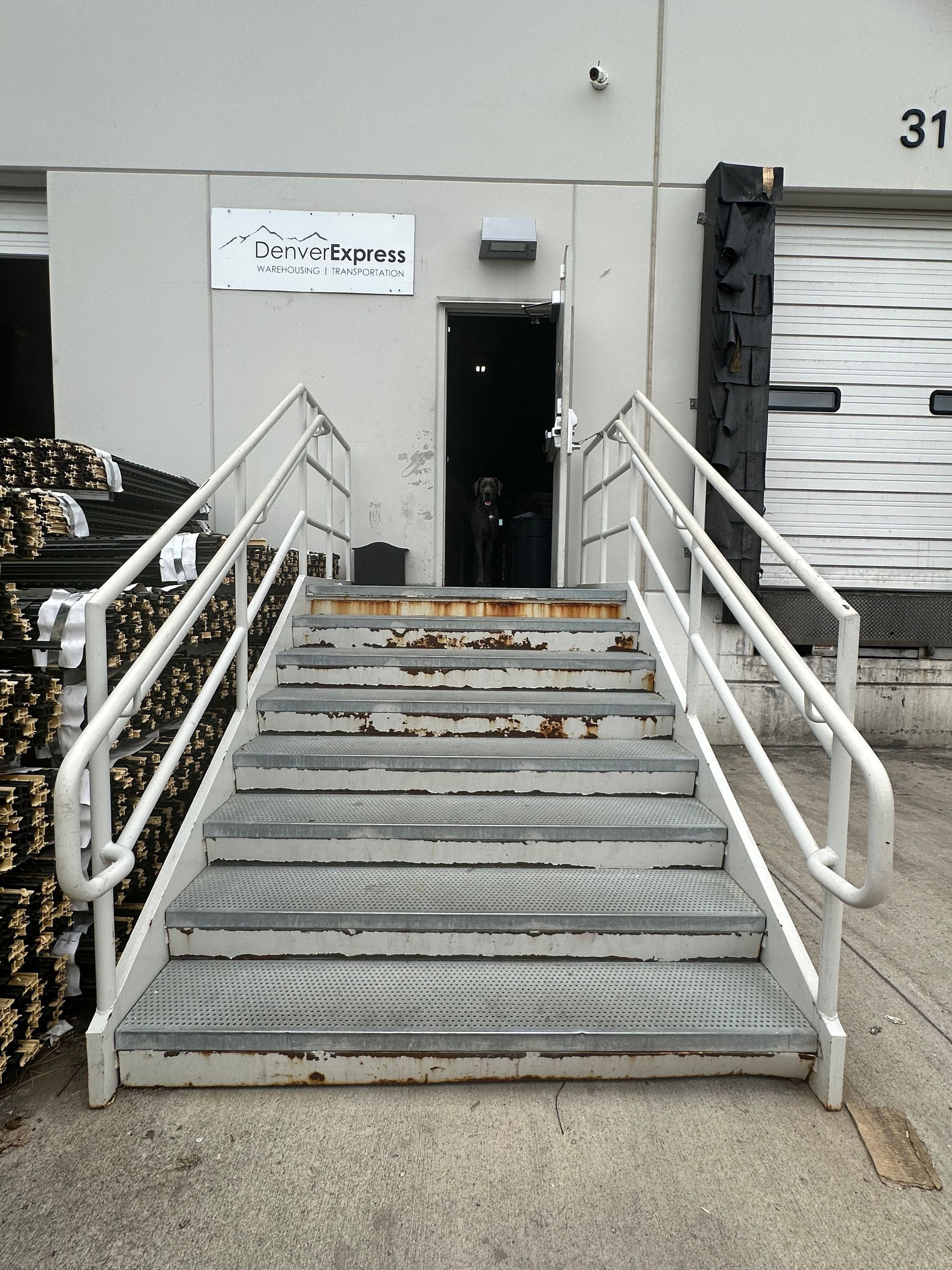 Metal stairs leading to a doorway, with handrails on either side. A loading dock door is visible to the right.