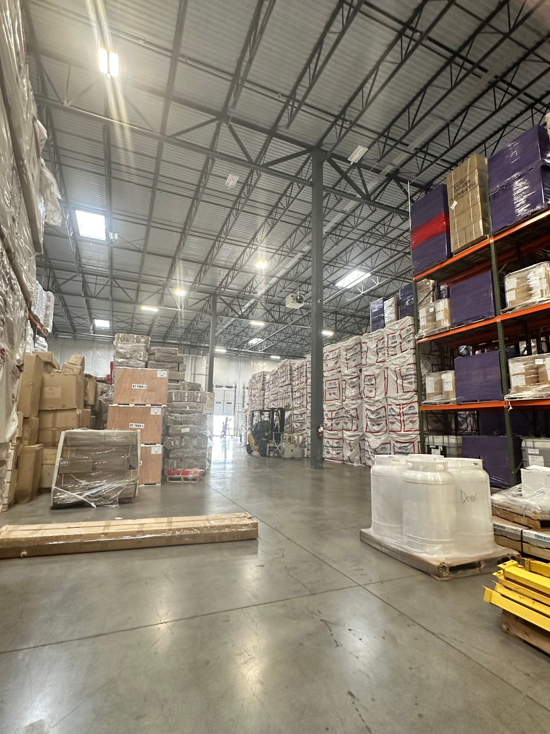 Warehouse interior with stacked boxes, shelves, and loading bay.