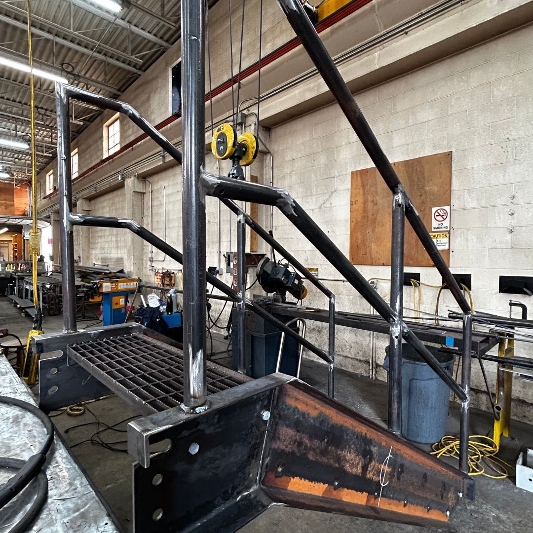 A metal staircase is being built in a factory