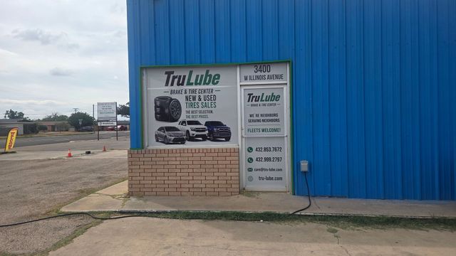 Sign on a blue building advertising Tri-Lube, with a brick base and parking lot in front