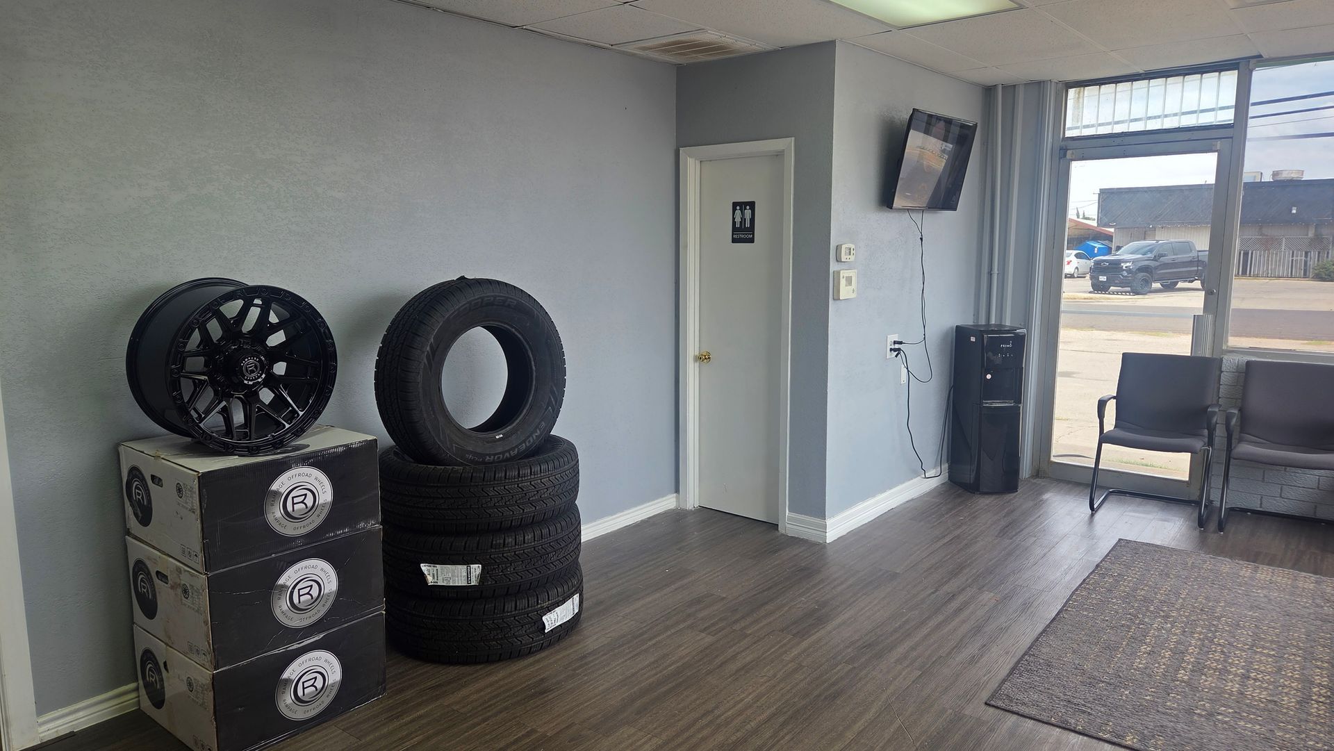 Small gym corner with tires, speaker, door, and chair near a sunlit window