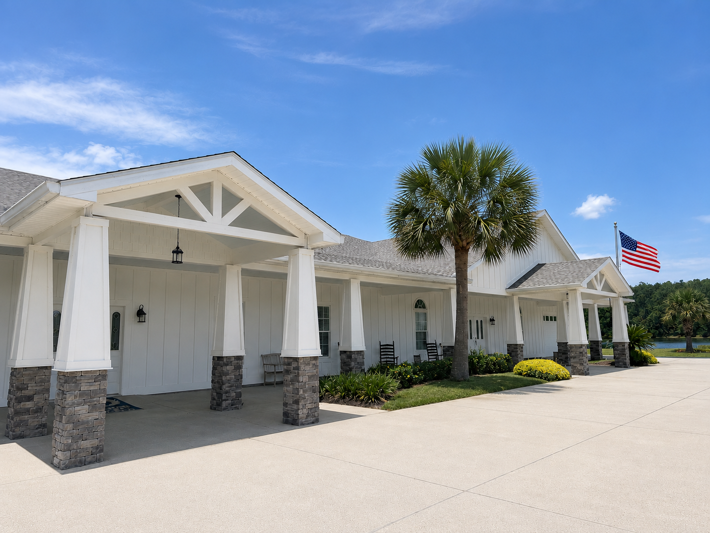 White house with black roof, palm trees, and a wide driveway under an overcast sky