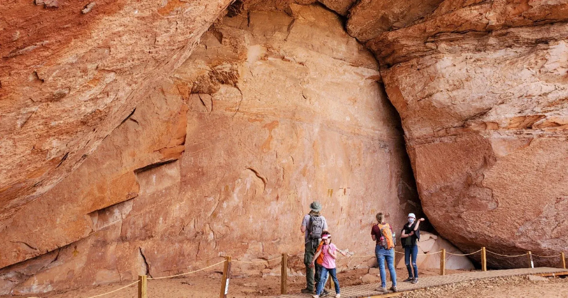A group of people standing in front of a large rock wall