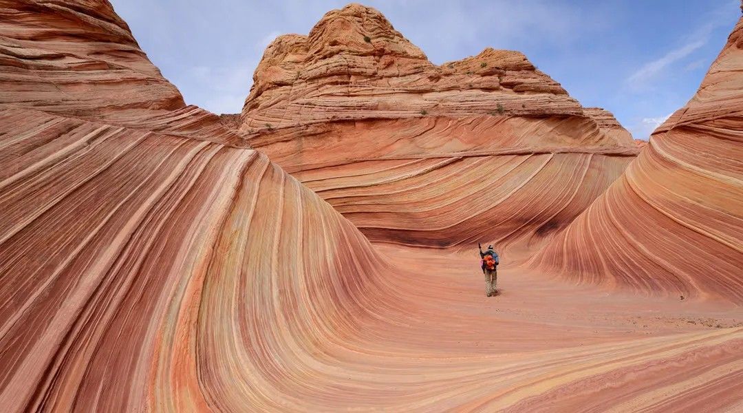 A person is standing in the middle of a canyon in the desert.