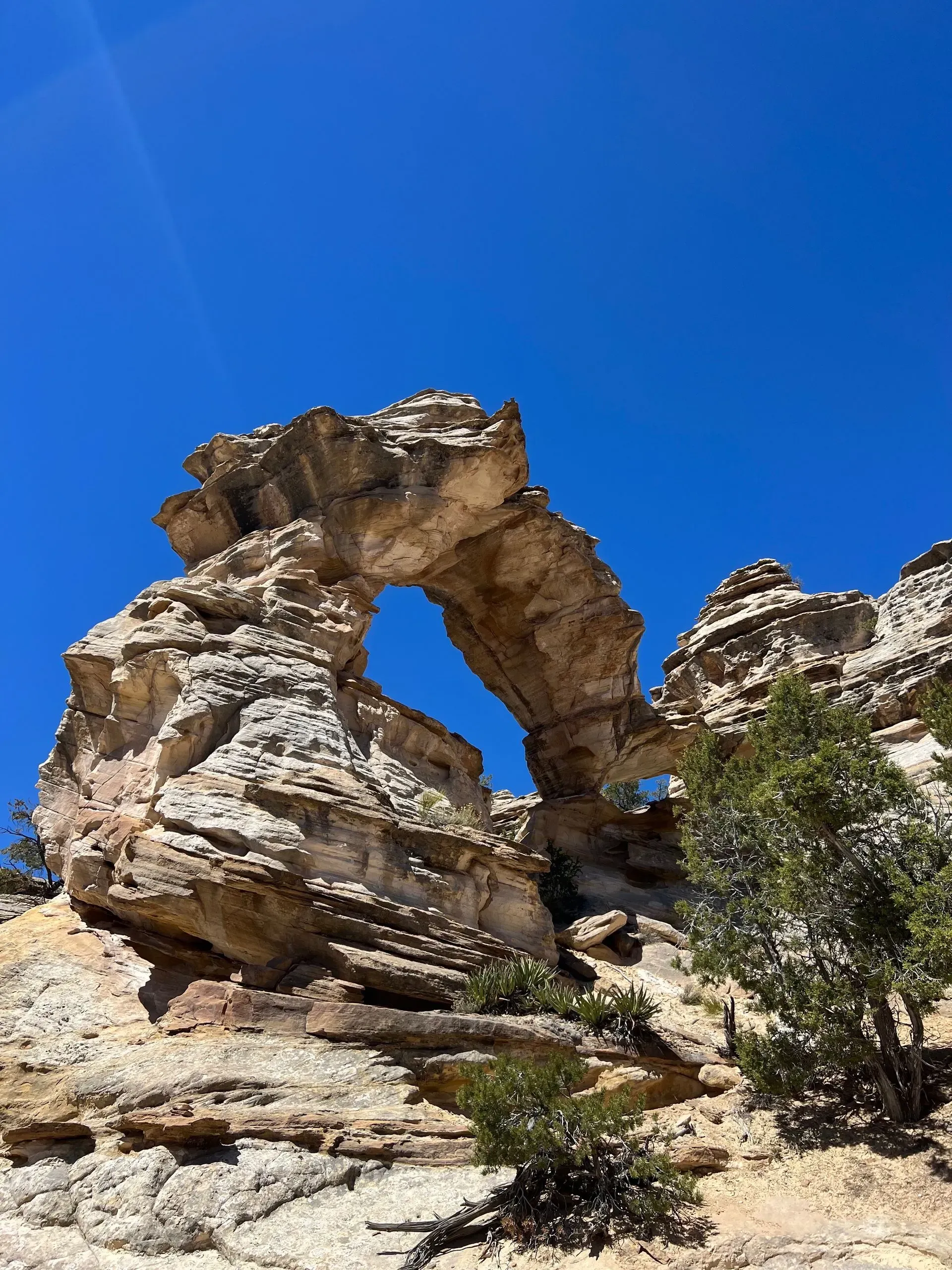 Natural stone arch in a rocky desert landscape under a bright blue sky