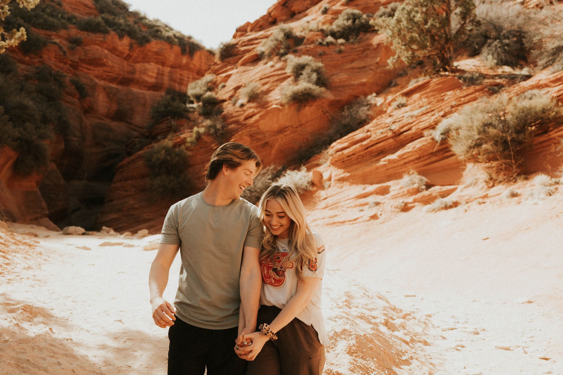 Couple standing together in a red rock canyon with bright white sand