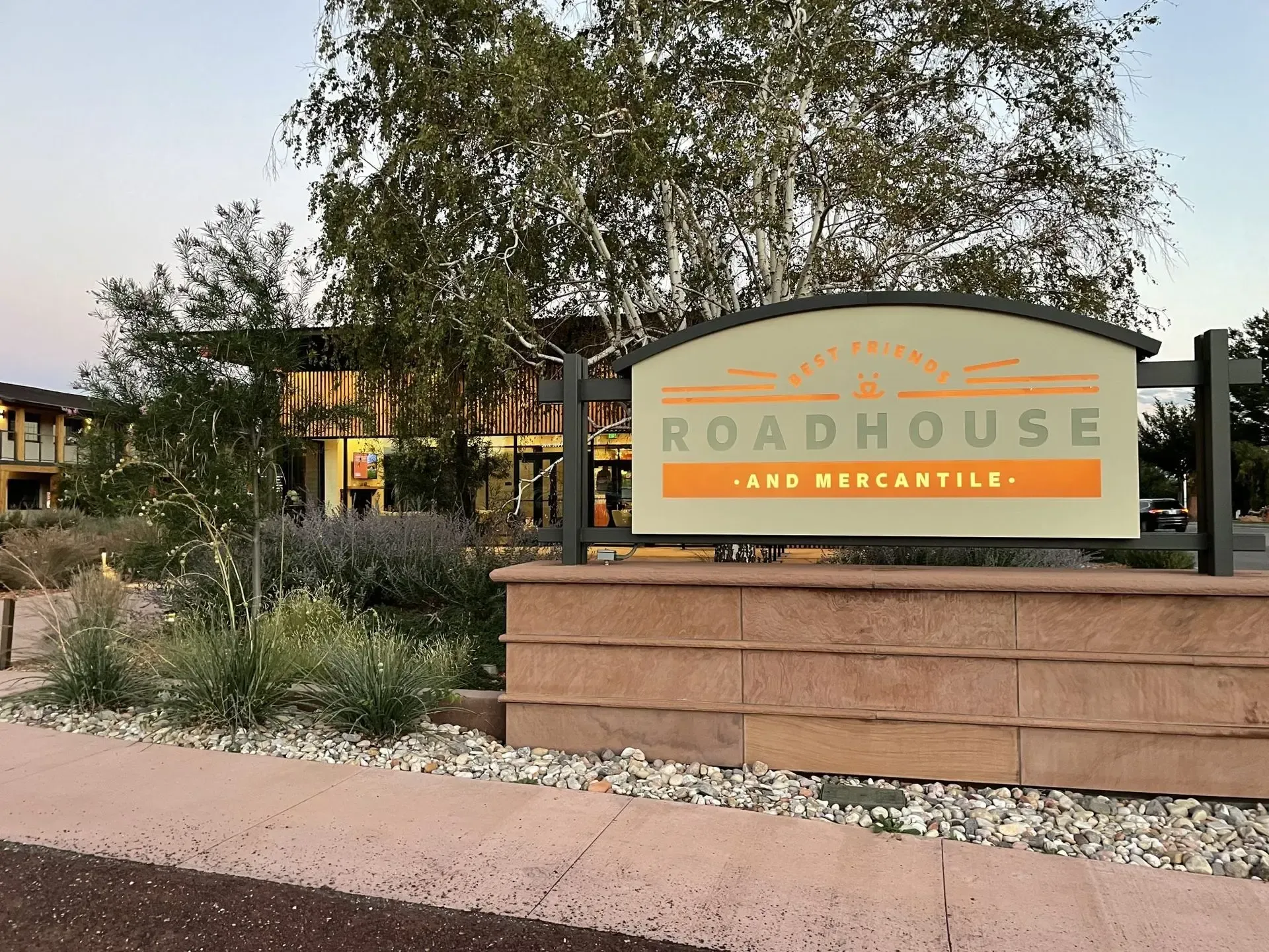 A roadhouse sign is sitting on a sidewalk in front of a building.