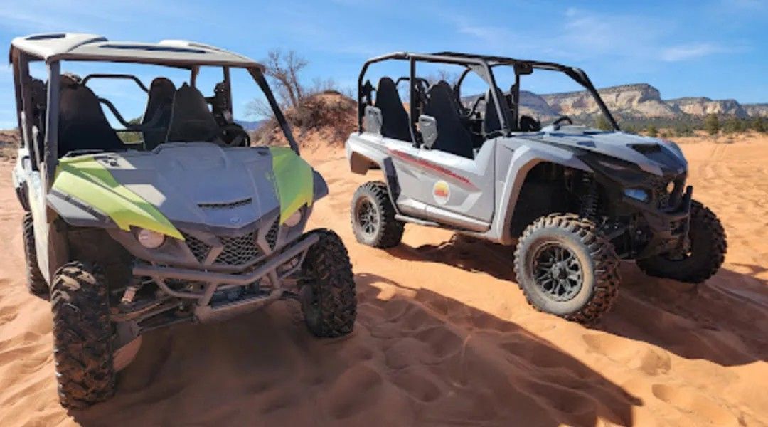 Two atvs are parked next to each other in the sand.