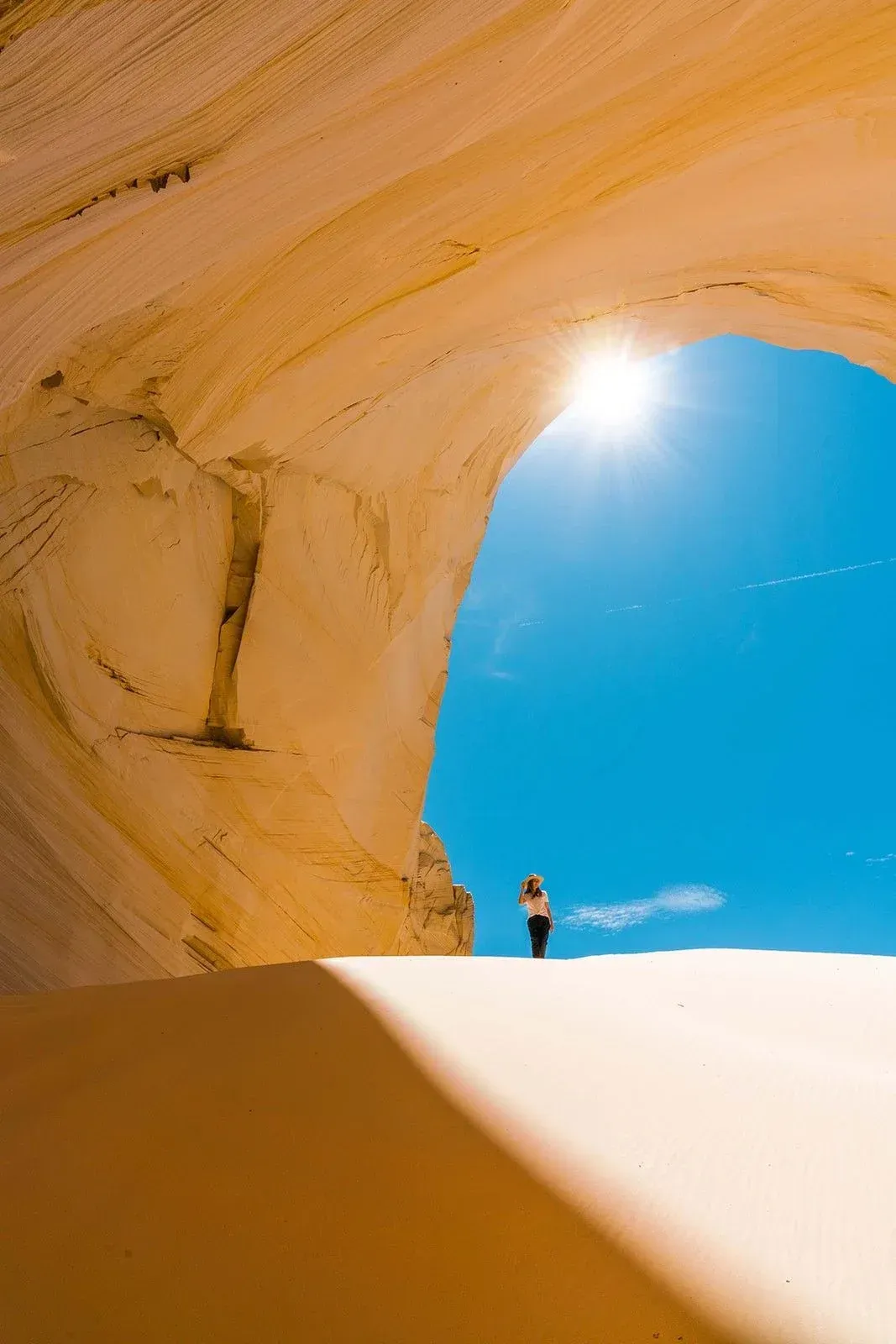 A woman is standing on top of a sand dune in the desert.