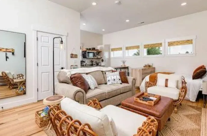 Bright, cozy living room with beige sofas, wood coffee table, and wicker chairs