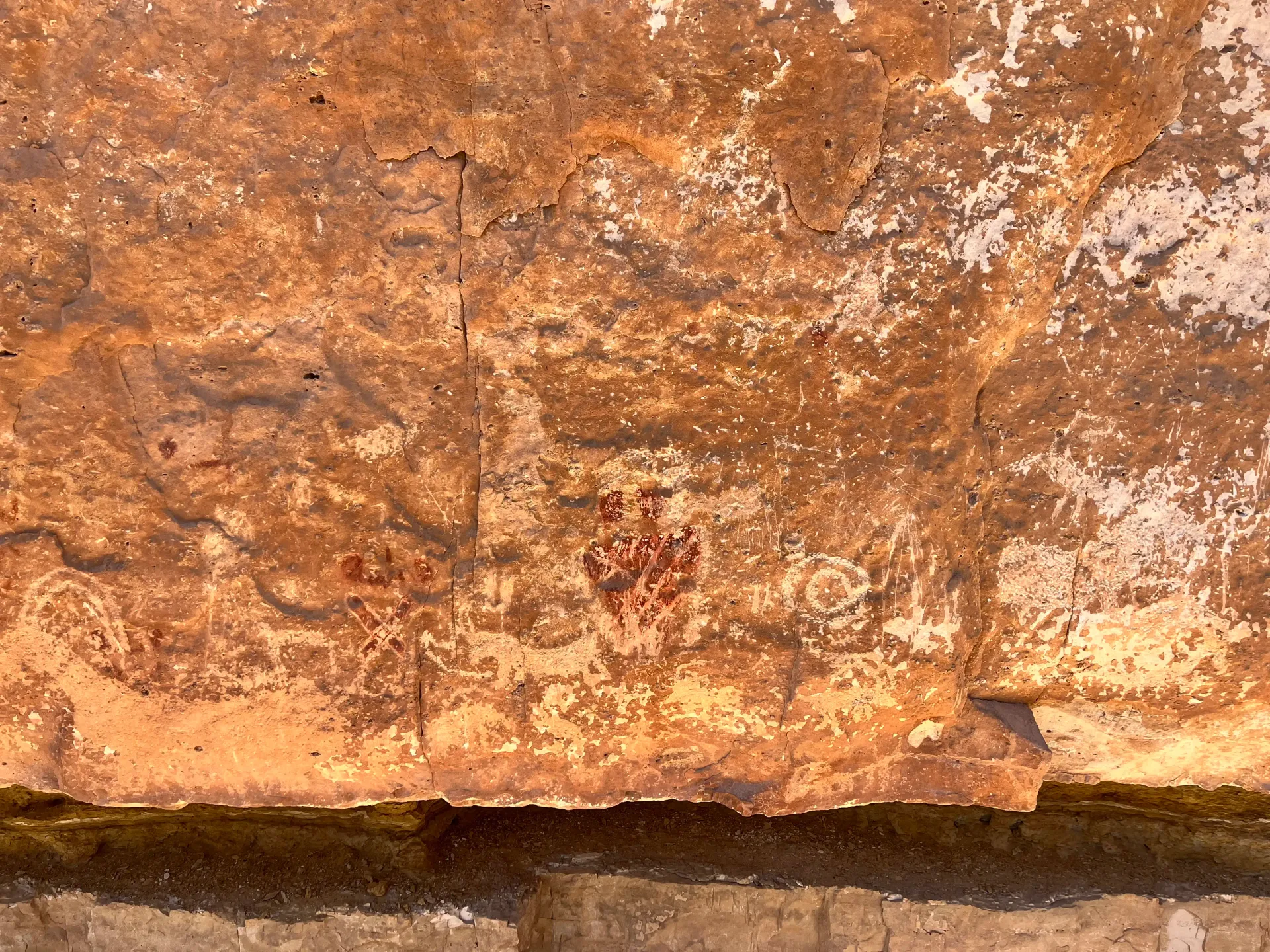 Close-up of a weathered orange-brown rock wall with rough texture and a dark crevice at the bottom