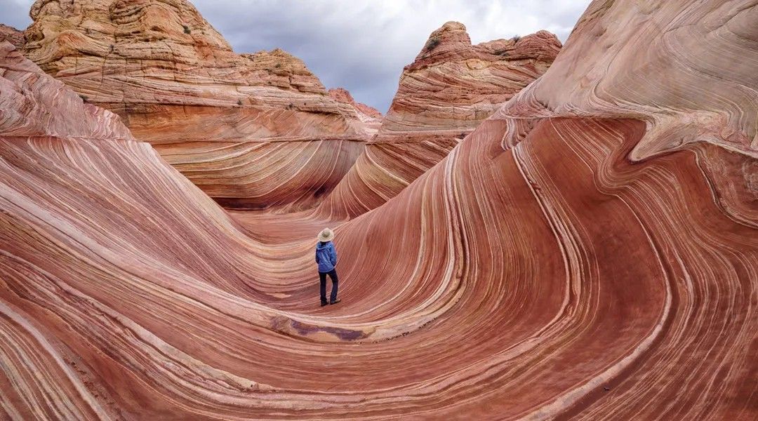 A person is standing in the middle of a canyon in the desert.