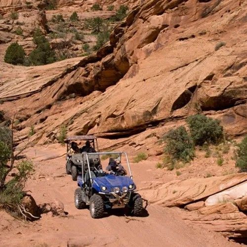 A blue atv is driving down a dirt road