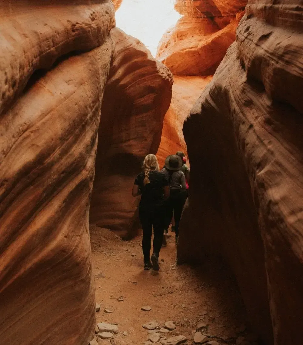 A group of people are walking through a canyon.