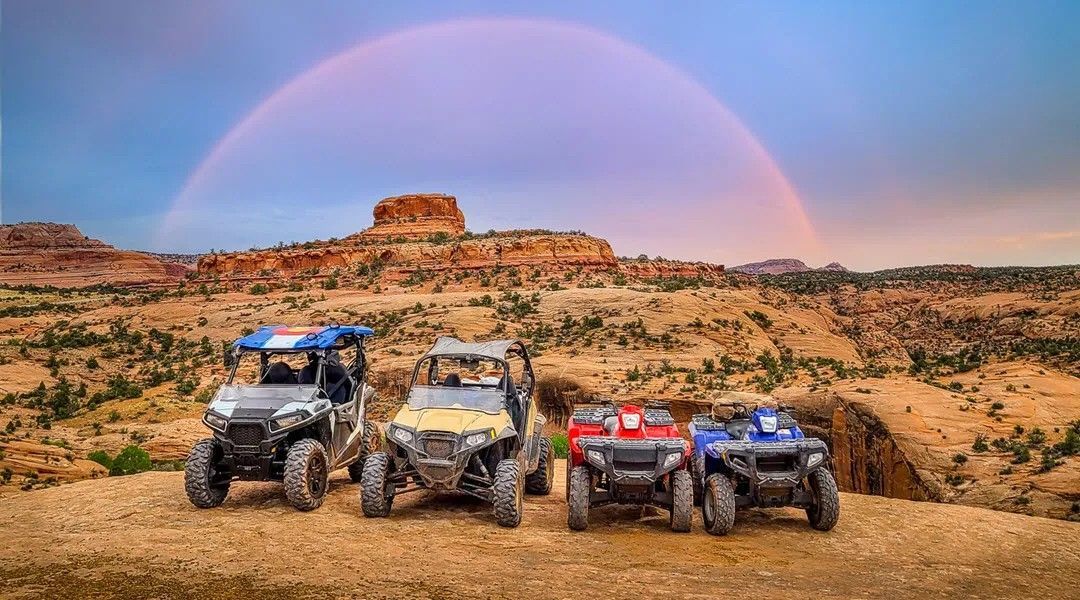 A blue atv is driving down a dirt road