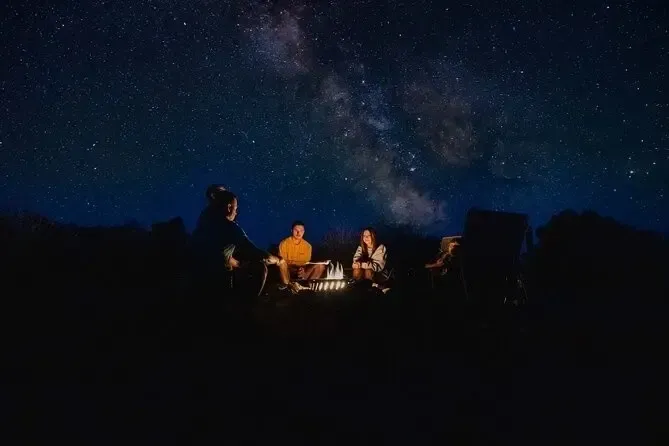 People around a campfire under a starry night sky