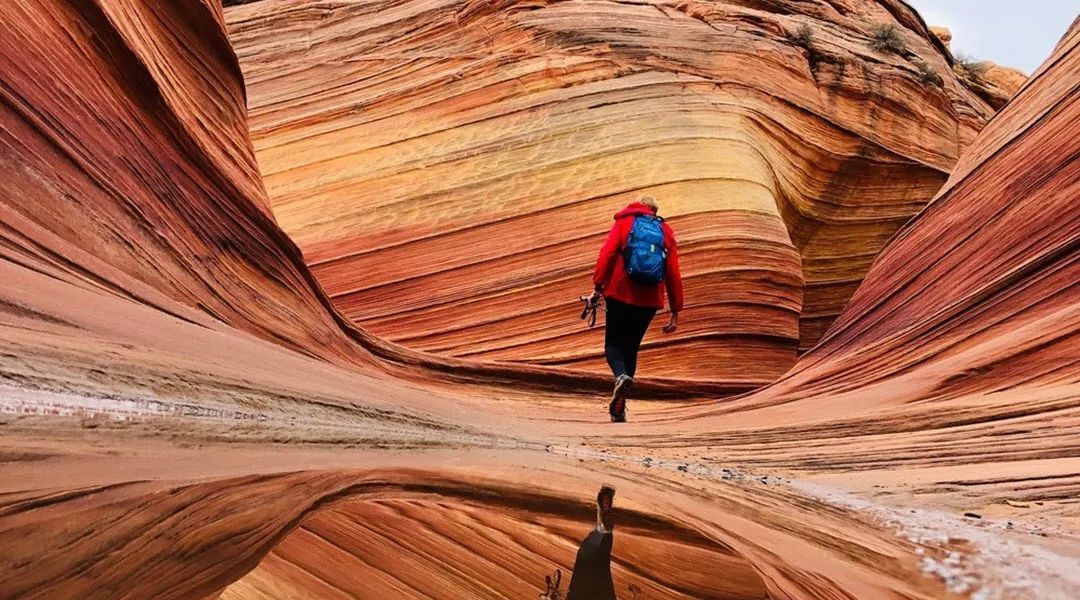 A person with a backpack is walking through a canyon.