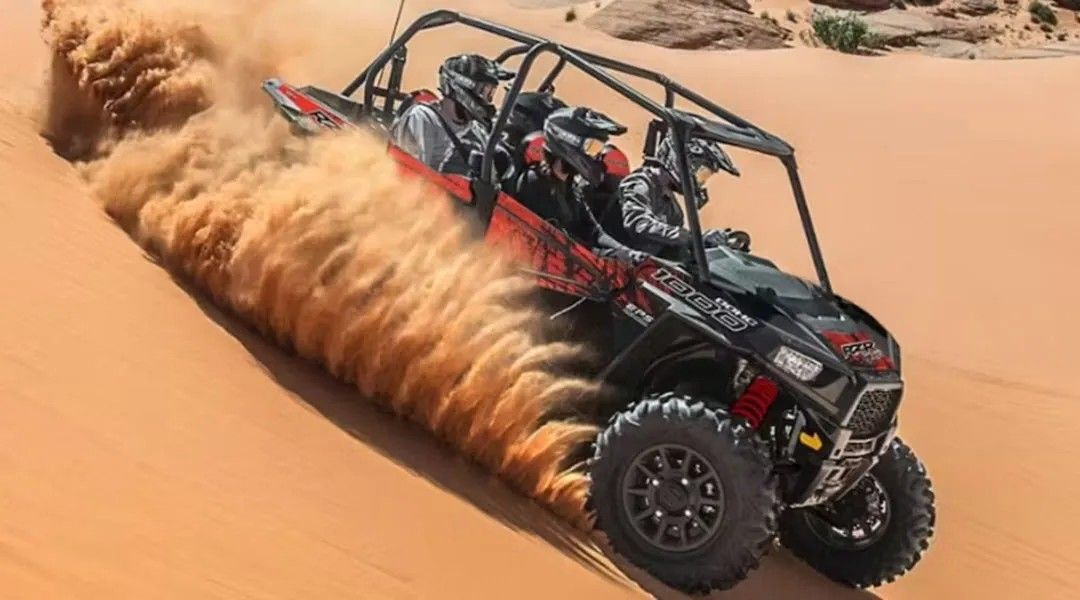 A person is riding a four wheeler through the sand in the desert.