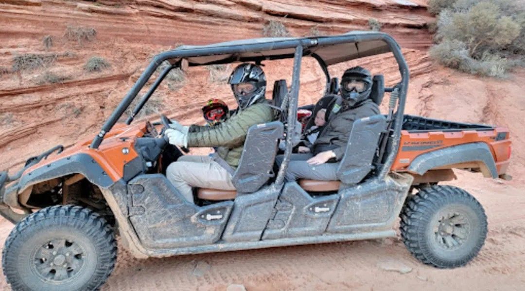 A couple of people are riding in a atv on a dirt road.