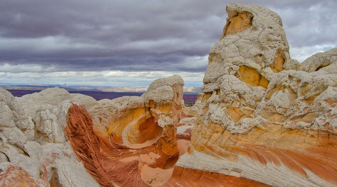 A rock formation in the desert with a cloudy sky in the background.