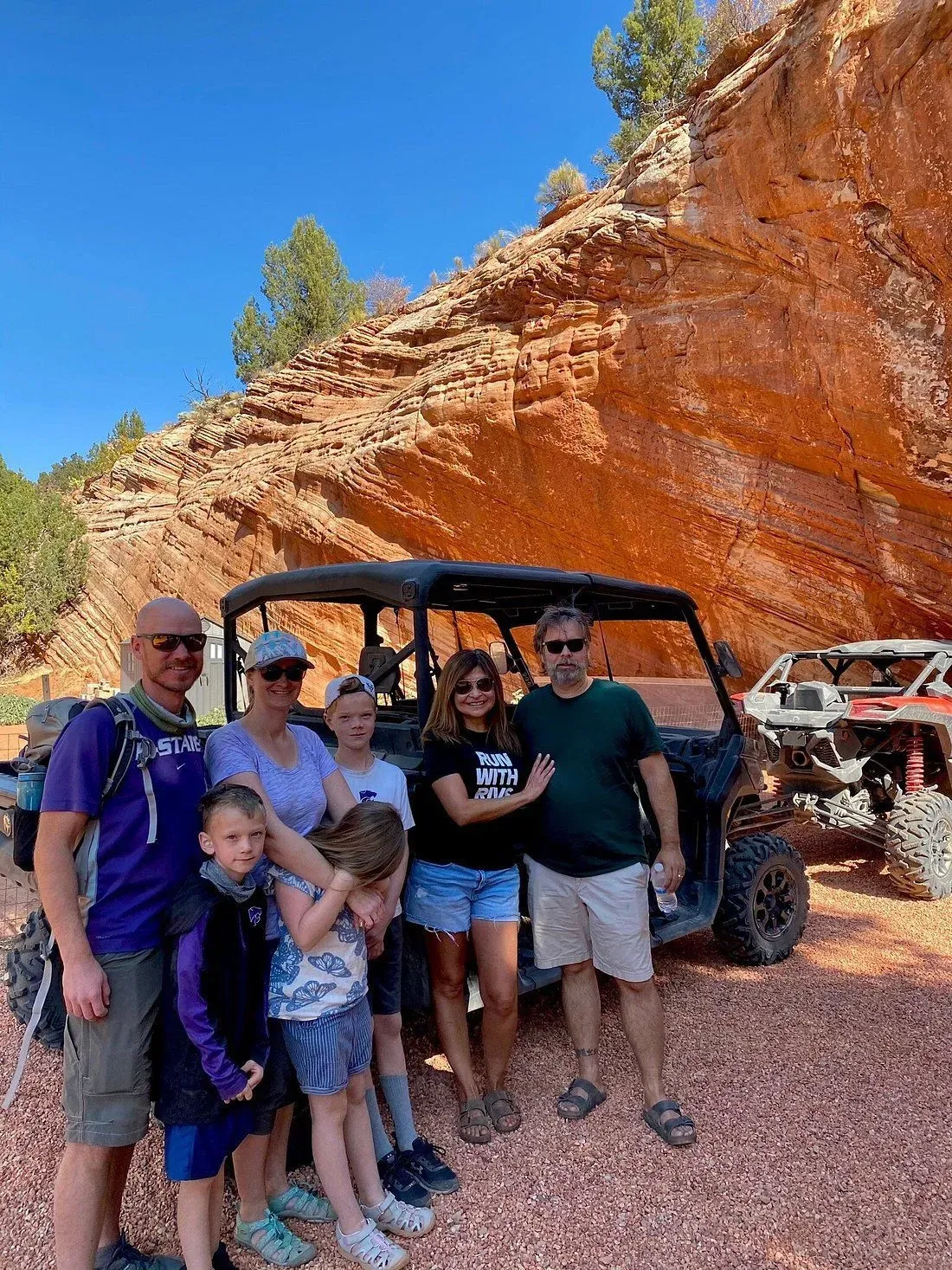 A family is posing for a picture in front of two atvs.