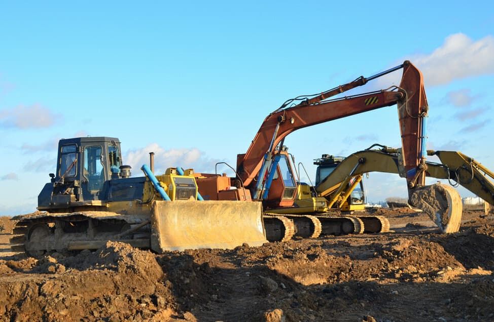 A Bulldozer And An Excavator Are Parked In A Dirt Field — Northstar Excavations In Byron Bay, NSW