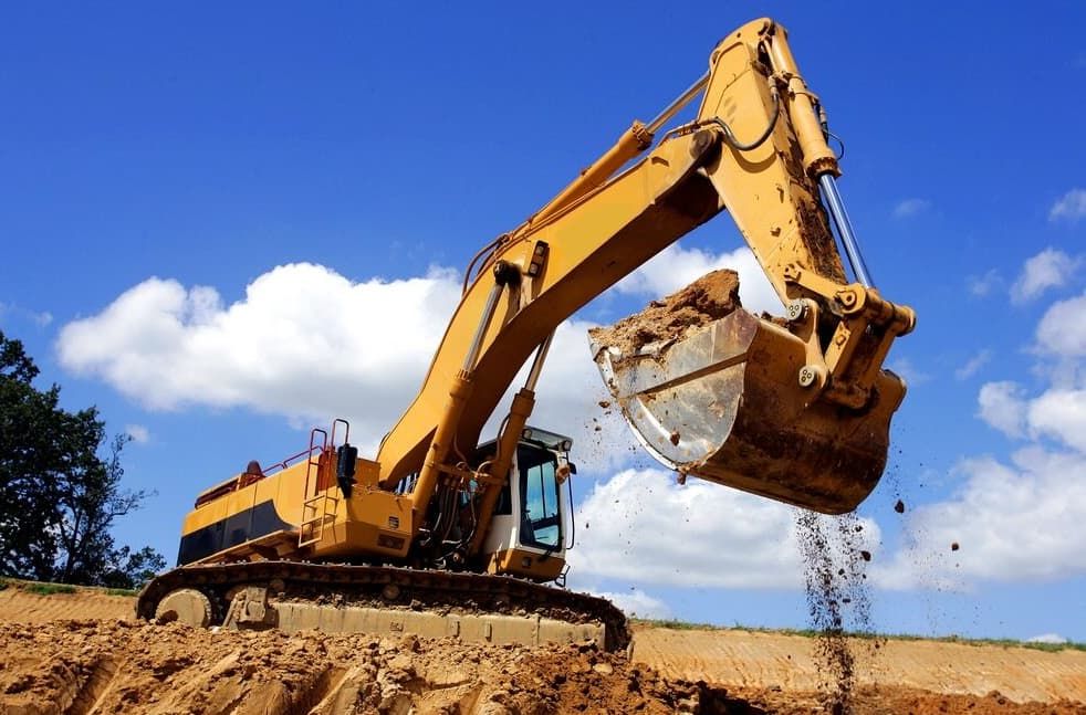A Large Yellow Excavator Is Digging A Hole In A Dirt Field — Northstar Excavations In Alstonville, NSW