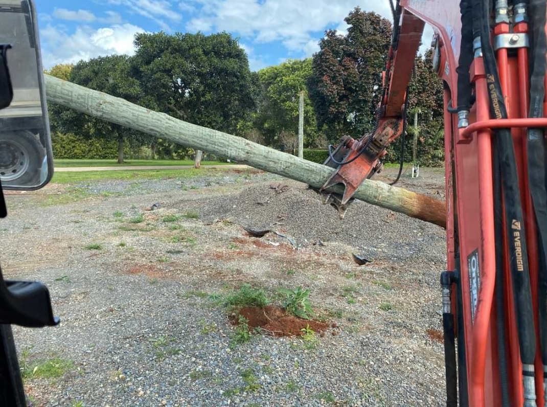 A Red Tractor Is Parked In A Gravel Lot Next To A Tree — Northstar Excavations In Alstonville, NSW