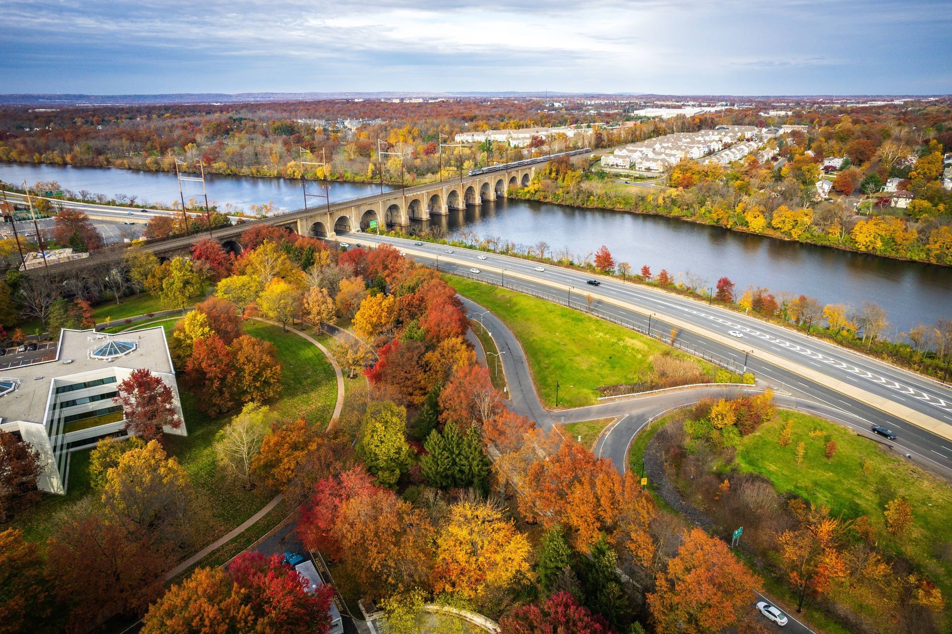 An aerial view of a bridge over a river surrounded by fall foliage.