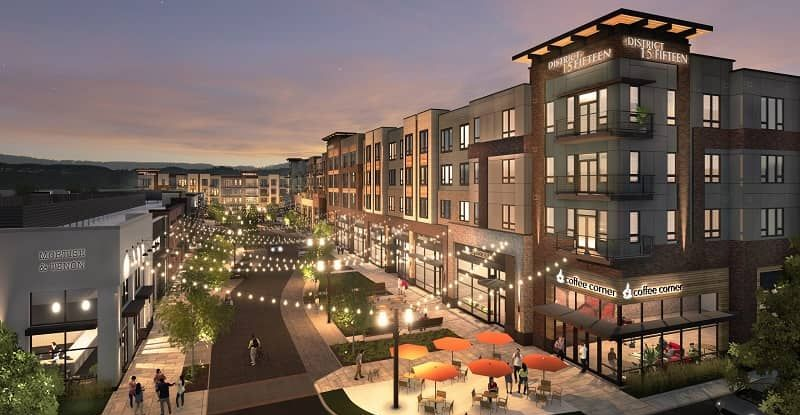 A twilight rendering of a modern mixed-use apartment complex with ground-level shops, string lights, and patio seating.