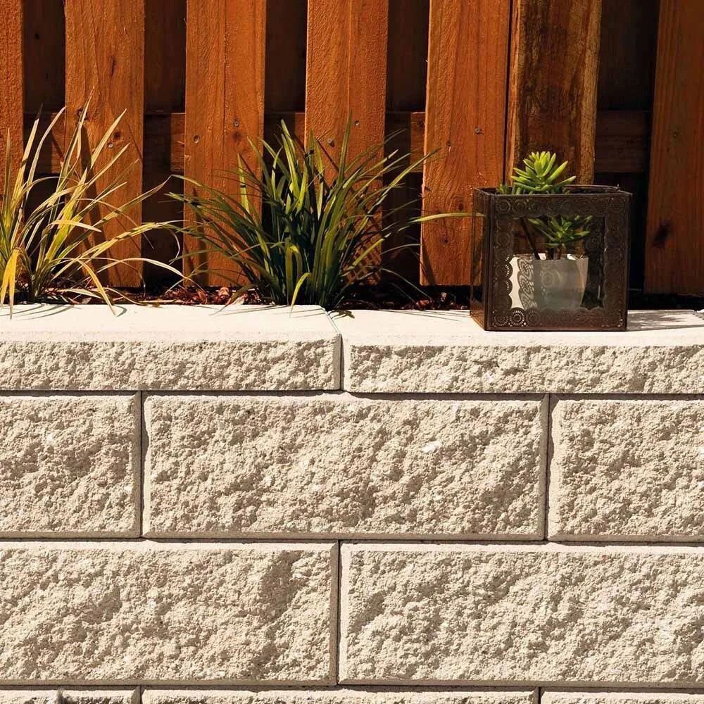 Stone Block Retaining Wall With Plants and a Wooden Fence Background — Hunter Valley Bricks & Pavers in Scone, NSW