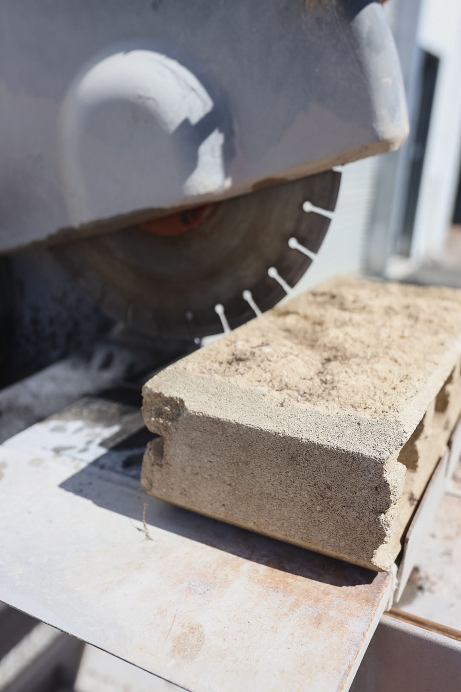 Circular saw cutting a concrete block on a workbench, with dust and saw blade visible — Hunter Valley Bricks & Pavers in Scone, NSW