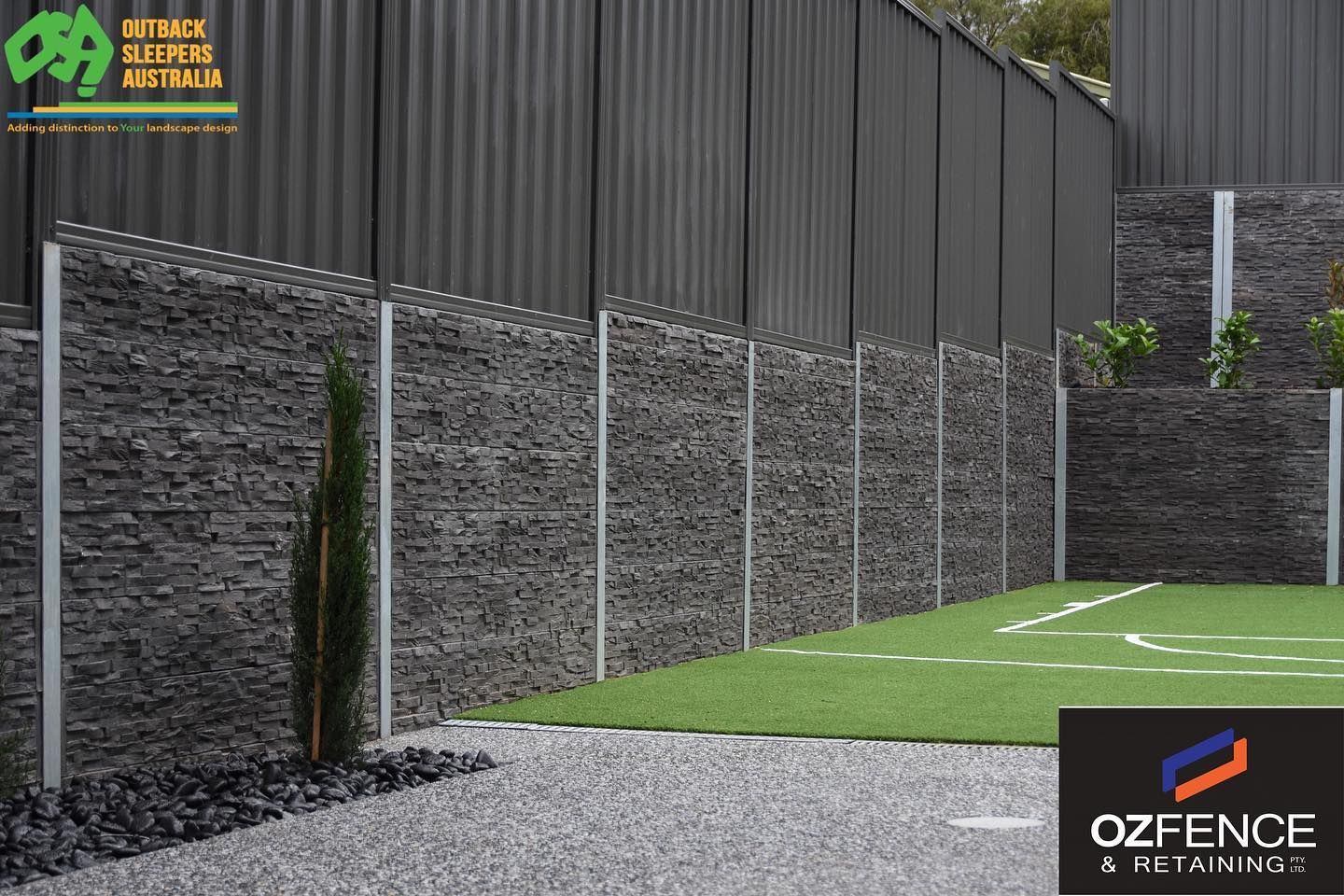 Modern stone-and-metal fence lining a landscaped gravel and grass yard