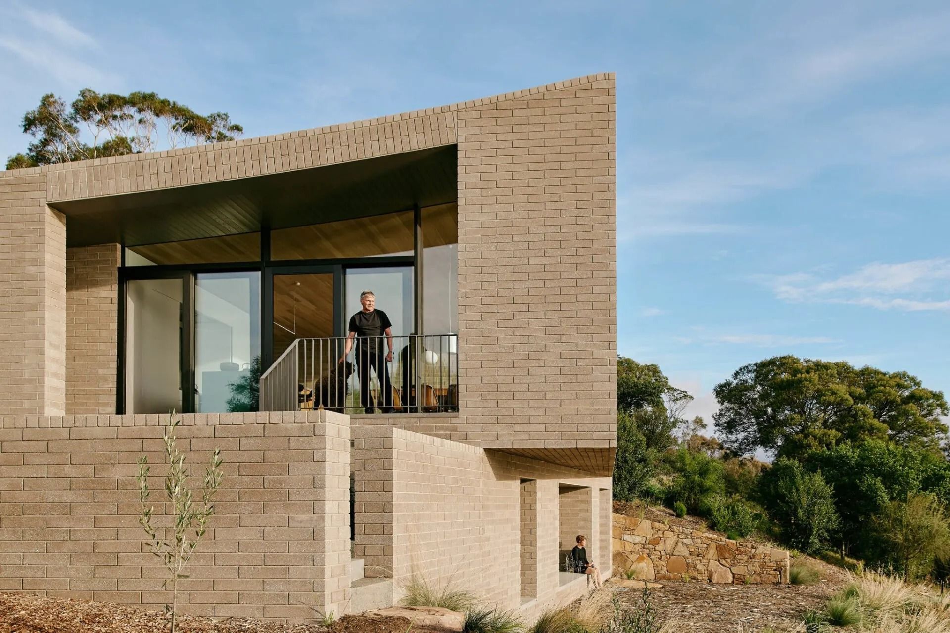 Man on Balcony of a Modern Brick House With a Hillside View — Hunter Valley Bricks & Pavers in Scone, NSW