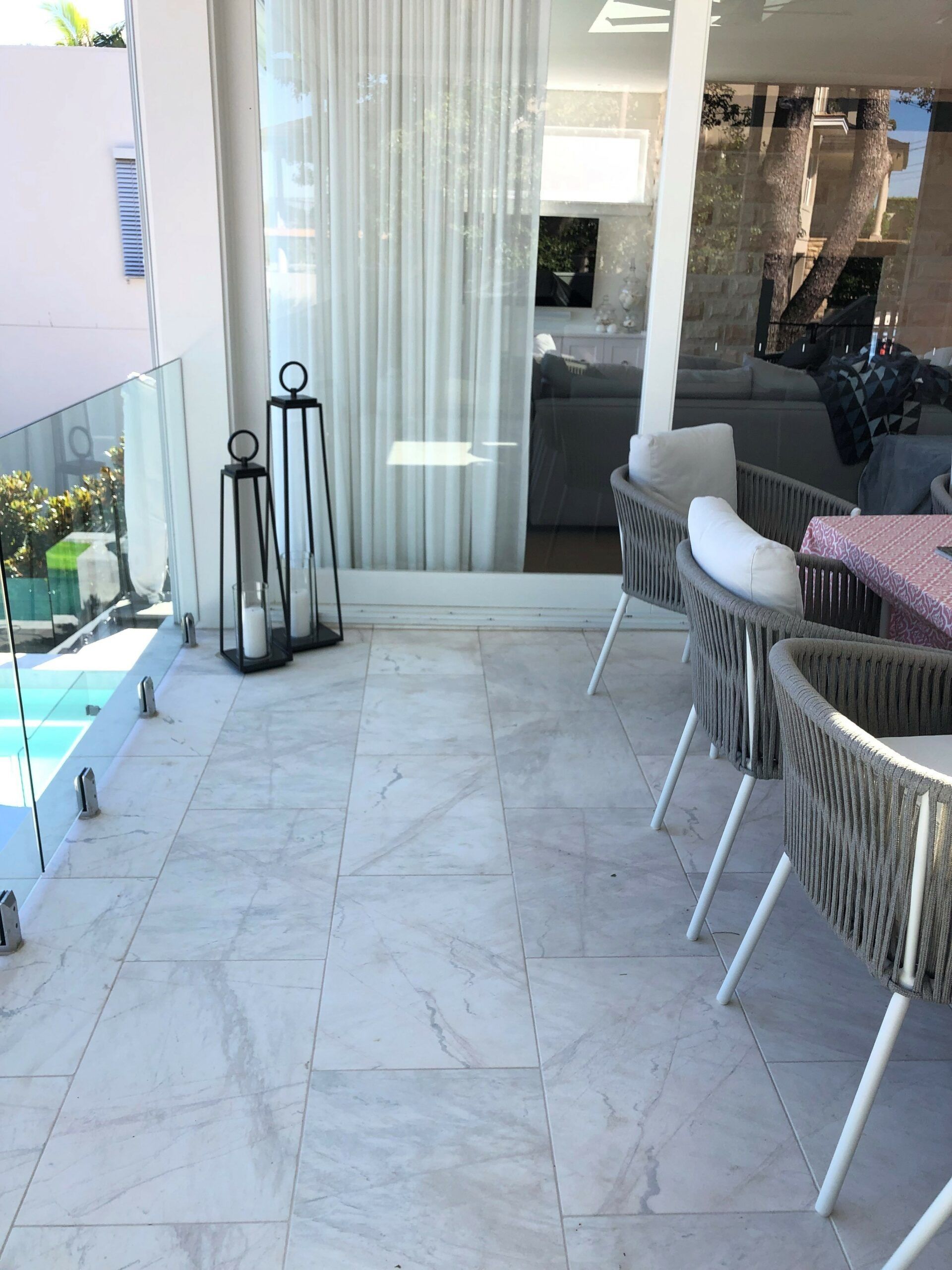 Outdoor Patio With Marble-like Tiles, Glass Railing, and Chairs — Hunter Valley Bricks & Pavers in Scone, NSW
