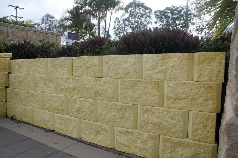 Yellow Retaining Wall Made of Large Stone Blocks, With Shrubs on Top — Hunter Valley Bricks & Pavers in Scone, NSW