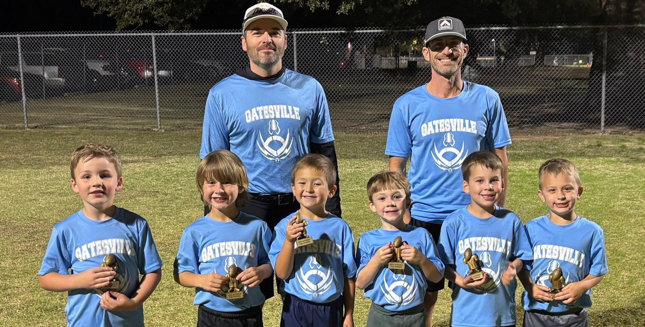 Youth baseball team and coach posing in blue jerseys on a field at night