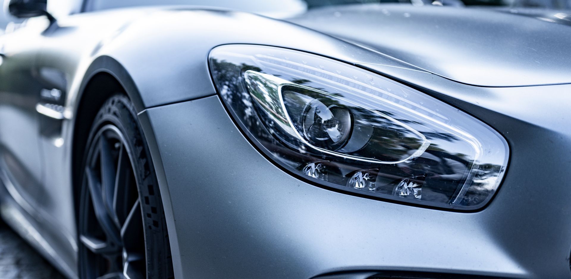 Silver sports car headlight, close-up.