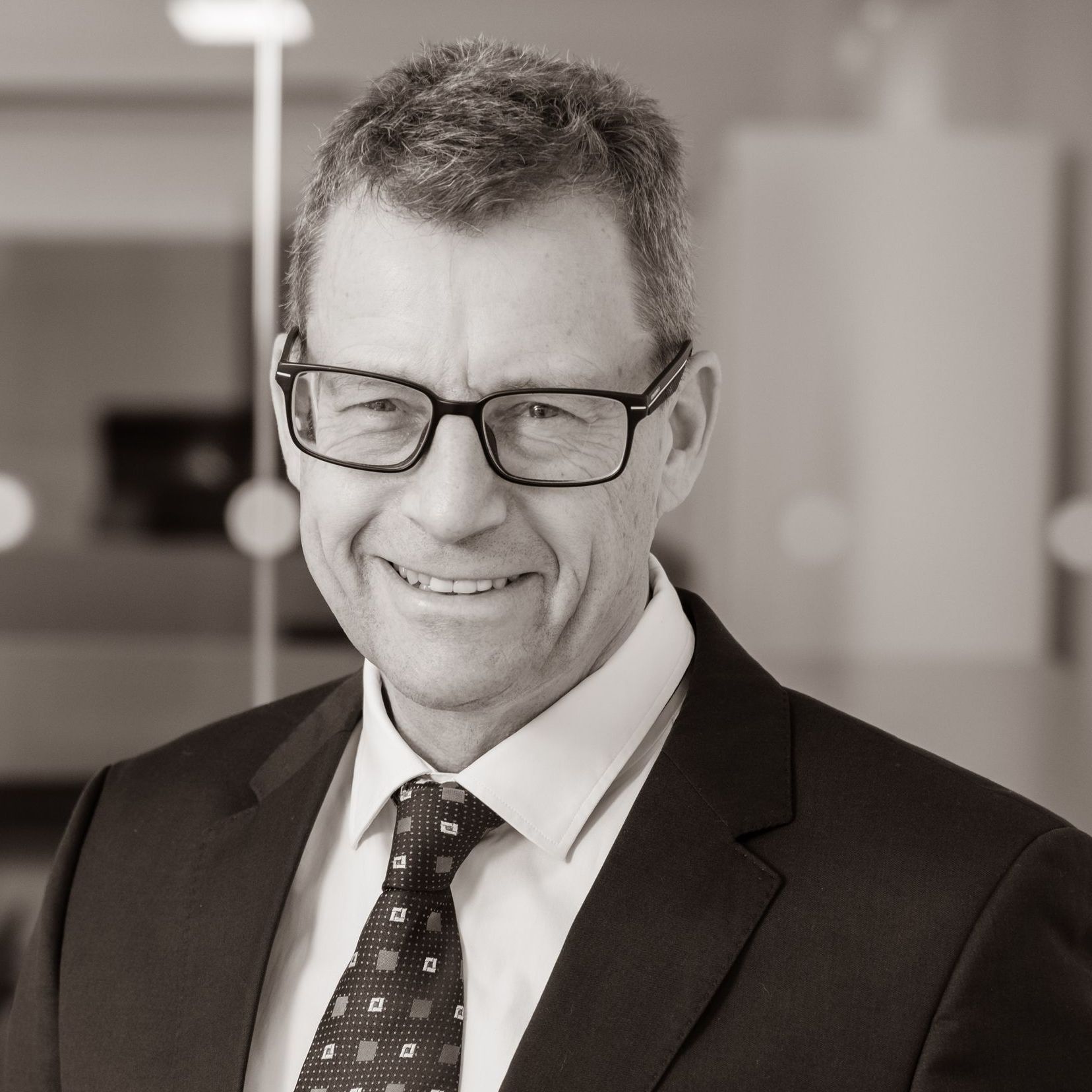A man in a suit and tie is smiling for the camera